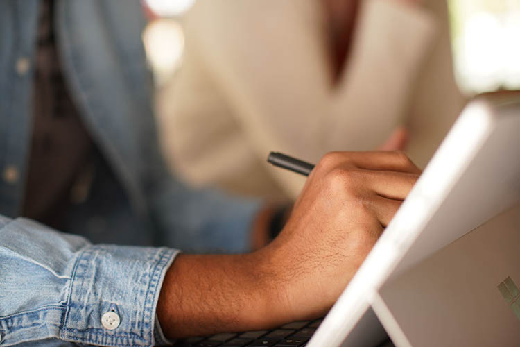 A person writing on a tablet.