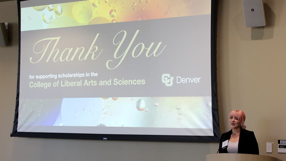 Student Elizabeth Kuhn standing at the lectern speaking in front of a big screen that reads "Thank You"