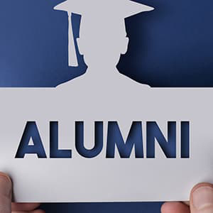 Silhouette of person wearing grad cap with the word alumni cut out below