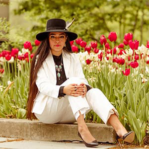 Anjelica Gallegos in a white pant suit sitting in front of a bed of tulips