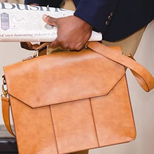 Person holding a briefcase and newspaper