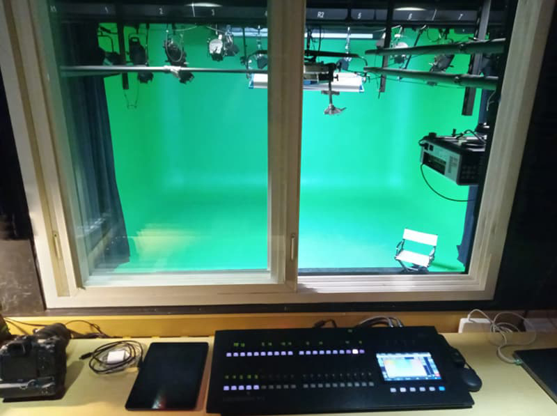 Image of a green recording room from the view of the engineer control panel.