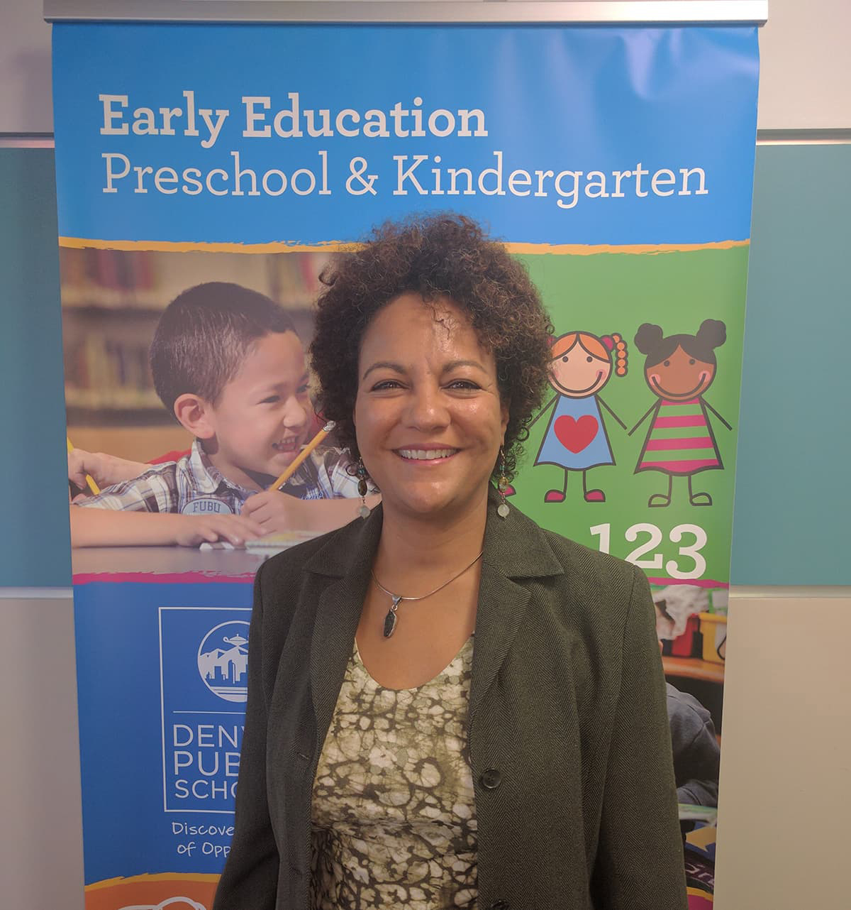 Photo of Lisa Roy smiling in front of an elementary school classroom.