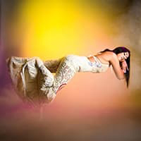 Image of Lolita laying down and seemingly floating on a yellow/gold background in a white flowy dress.