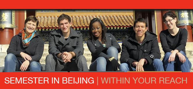 A group of five students seated in front of Chinese architecture smiling.