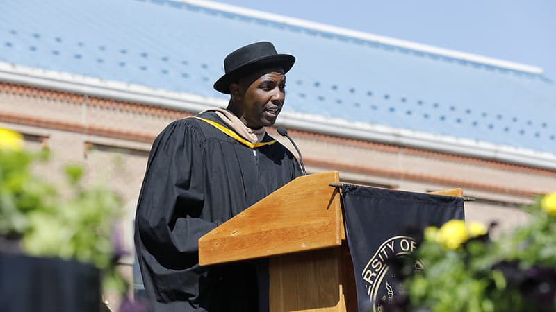 Thomas "Detour" Evans in CU Denver regalia speaking at a lectern for the Spring 2022 Commencement ceremony.