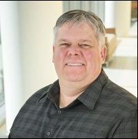 Headshot of Daniel Matlock from the chest up smiling in business casual shirt.