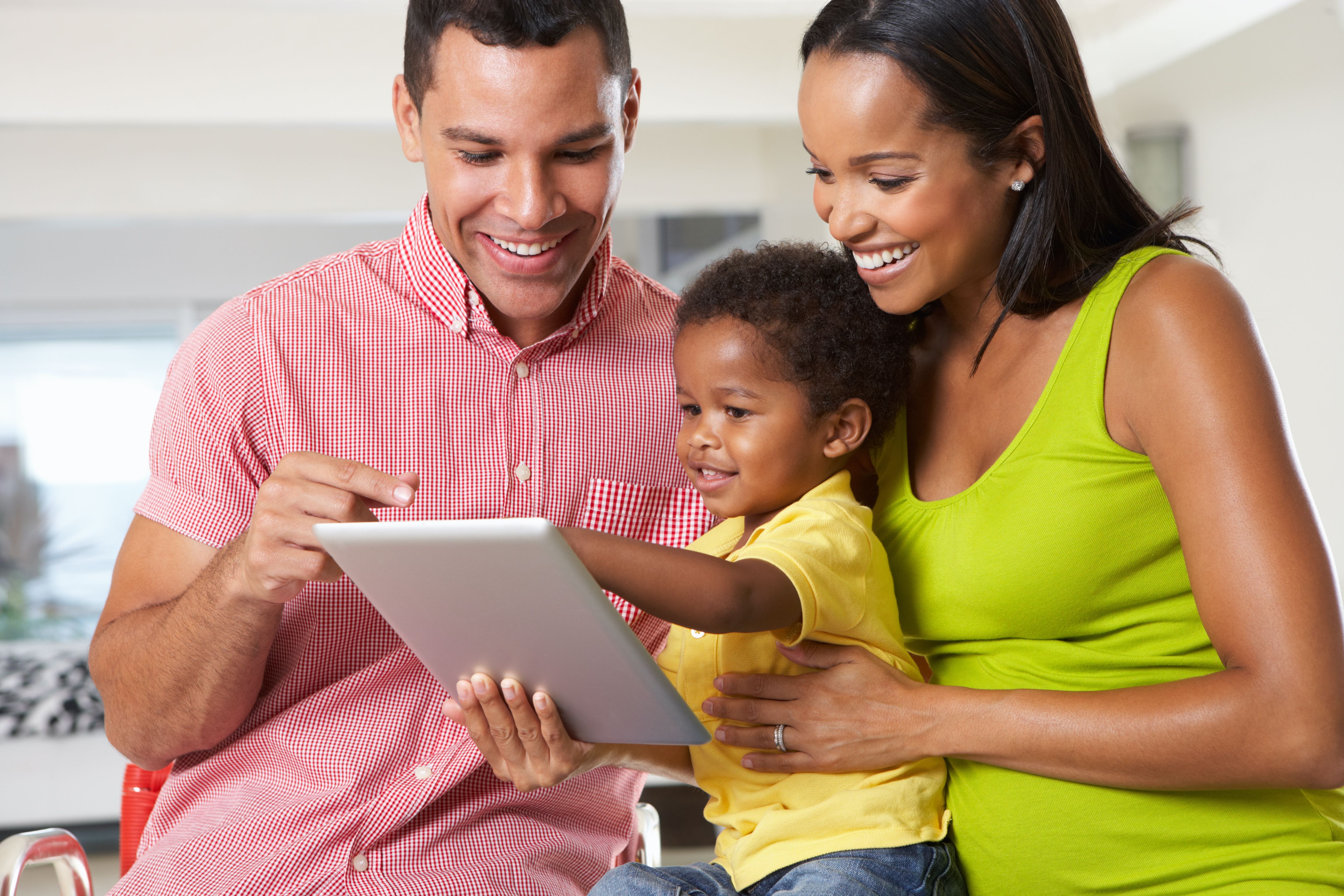 Parents holding child using tablet together.