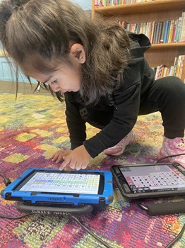 Young girl happily using her Accent device to communicate.