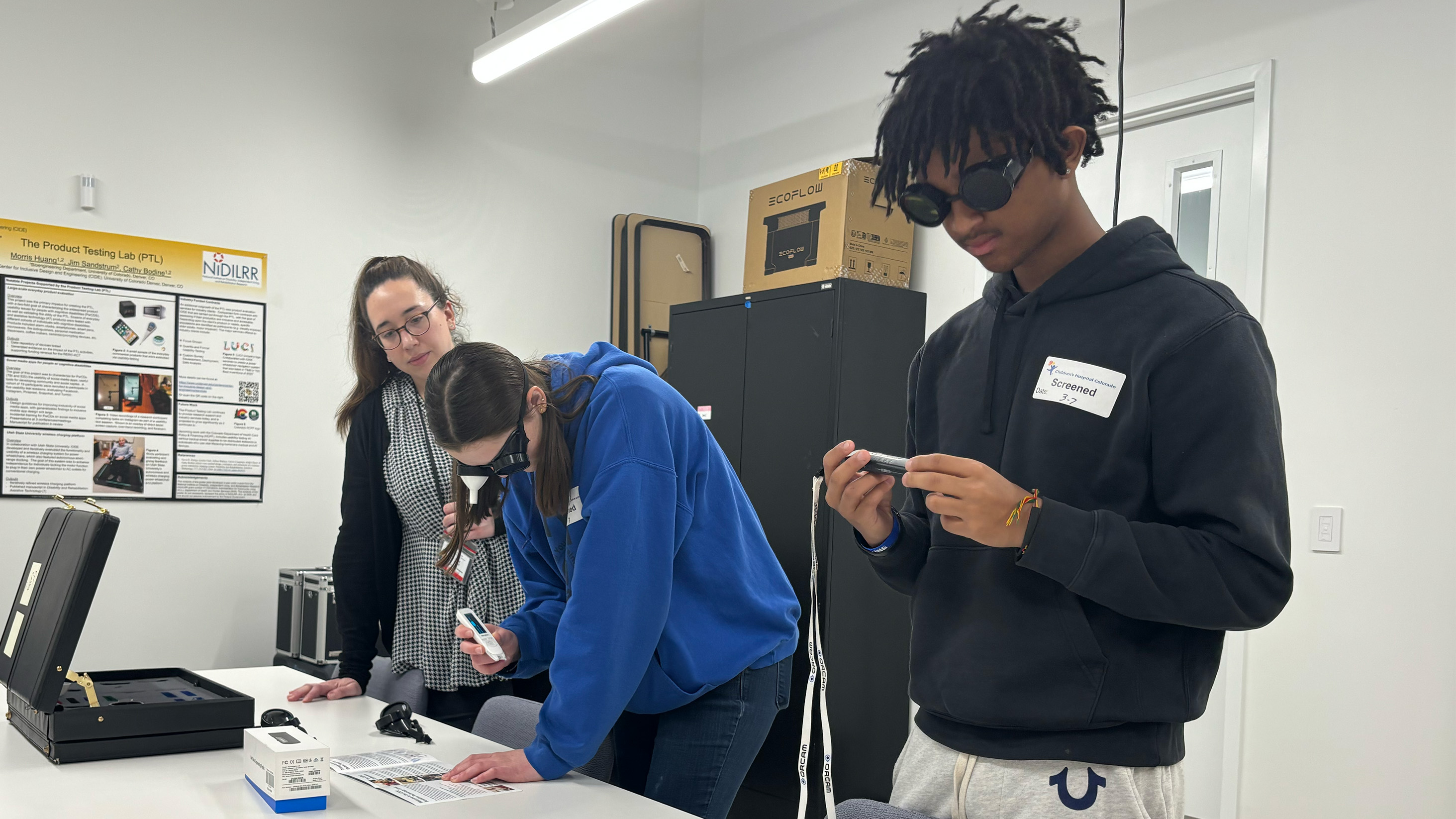 High schoolers trying on goggles that simulate visual impairments while CIDE member Leslie Emery supervises.